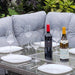 Mid Ulster Garden Centre Amalfi dark grey rattan dining set with firepit table, wine bottles, and place settings.
