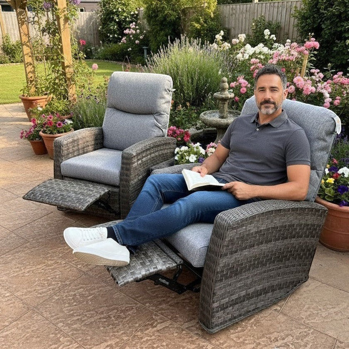 Man relaxing in a Mid Ulster Garden Centre Amalfi grey wicker recliner chair in a lush garden setting.