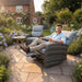 Man relaxing on a Mid Ulster Garden Centre Amalfi recliner chair in a lush garden with a matching bistro table.