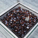 Mid Ulster Garden Centre Amalfi firepit table center with dark amber glass stones and protective glass surround