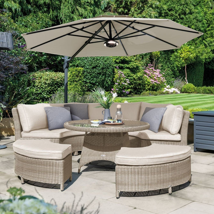 Mid Ulster Garden Centre Kettler Palma round wicker sofa set in oyster with stone cushions and a large garden parasol.